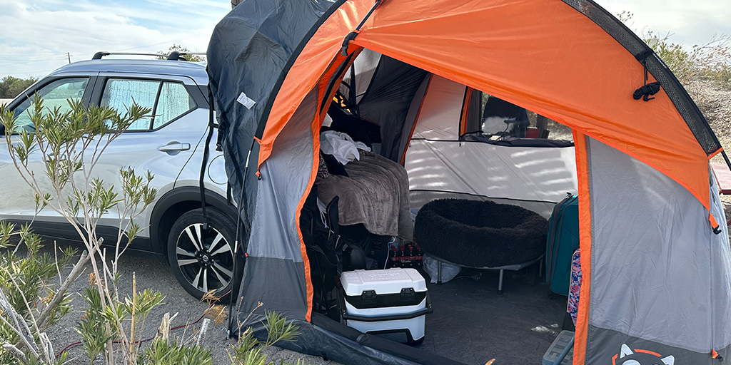 A tent wraps over an open hatchback.