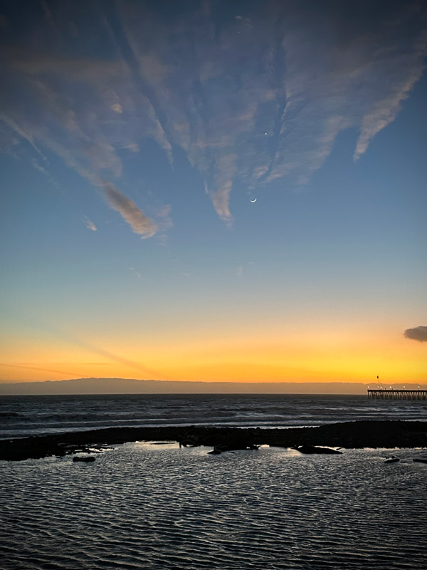 Beach scene showing the last bit of sunset with the moon and a few stars appearing.